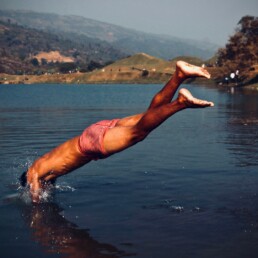 A man in swimsuit diving into a body of water.