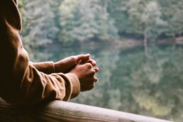 A person's hands and arms are visible leaning against a railing.