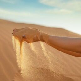 Hand holding sand and slowly letting it fall between their fingers.