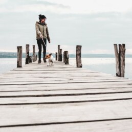 A woman walking a dog on a dock.